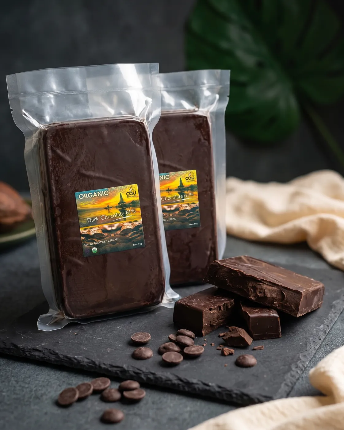 AI visual — CAU organic dark chocolate couverture 1 kg packs on slate (real packaging, AI-styled background)