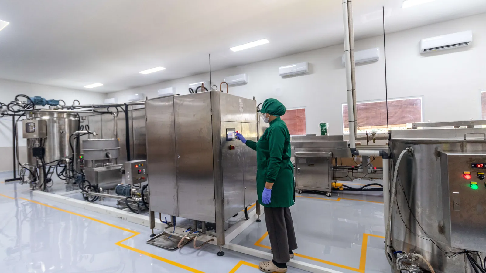 The CAU chocolate production room, with stainless steel machinery and a team member at the controls